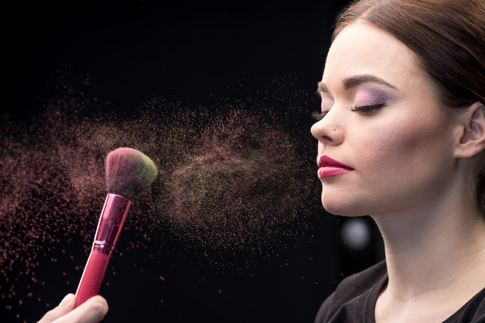 make-up-artist-sprinkling-model-s-face-with-powder-with-help-of-brush-on-black.jpg